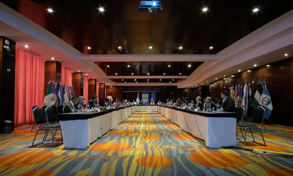 Vista de una sala de reuniones con personas sentadas alrededor de una mesa larga.
