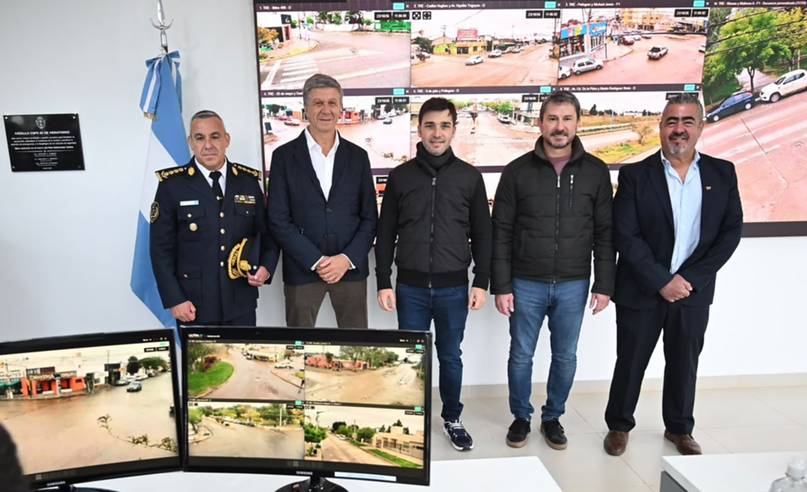 Cinco personas posan frente a monitores con imágenes de cámaras de calles, junto a una bandera argentina.