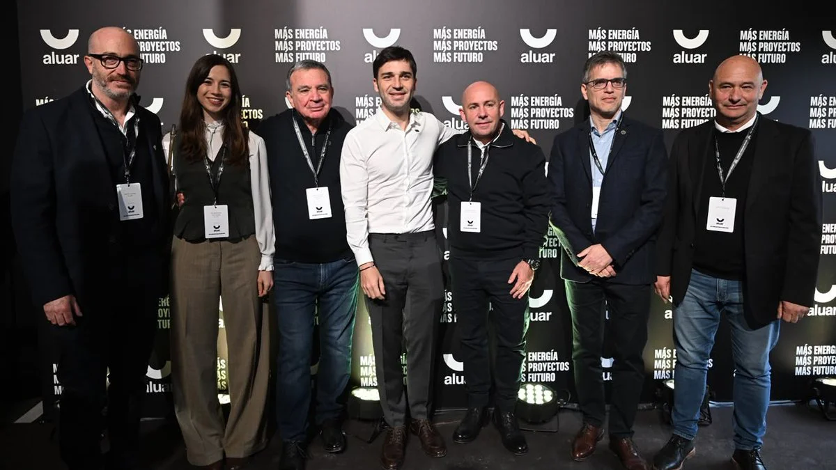 Un grupo de siete personas posa frente a un fondo negro con el logo de Aluar y la frase Más energía, más proyectos.