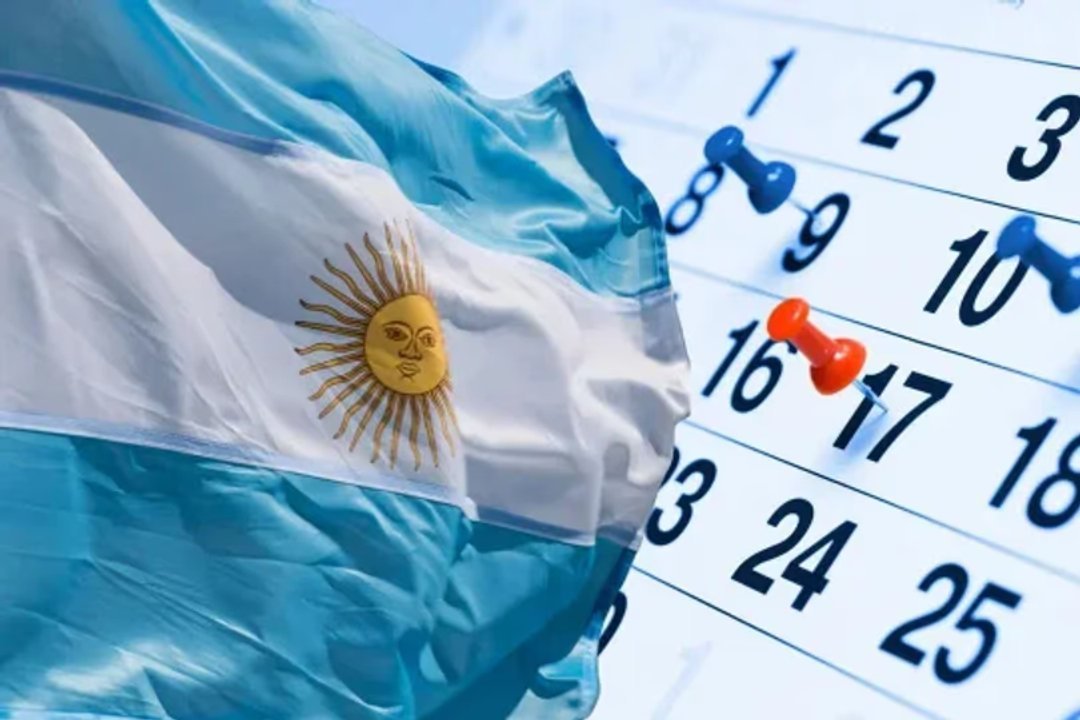 Una bandera argentina ondea junto a un calendario con chinches de colores clavados sobre algunos días.