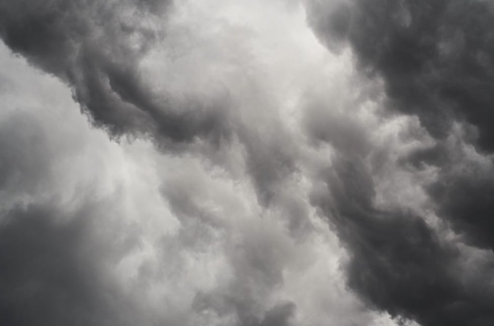 Vista de nubes grises y oscuras cubriendo el cielo, con parches de luz entre ellas.