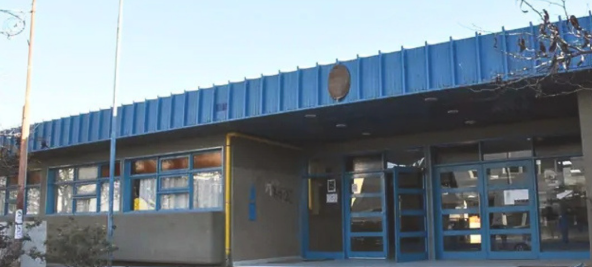 Vista de la fachada de un edificio con puertas de vidrio azules y techo de chapa azul