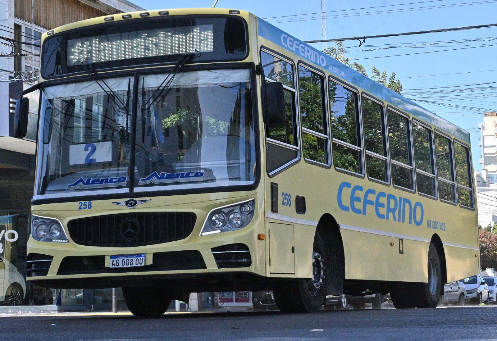 Un colectivo amarillo circula por una calle de la ciudad, con el cartel de destino encendido en el parabrisas.